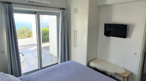a bedroom with a bed and a balcony with a television at Galini Breeze in Agia Galini