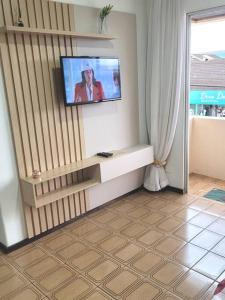 a living room with a television on a wall at Apartamento Brejatuba Beira Mar in Guaratuba