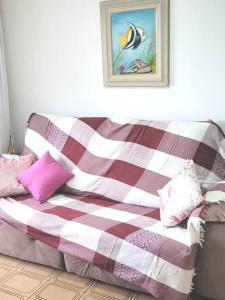 a couch with pink and white blankets and pillows at Apartamento Brejatuba Beira Mar in Guaratuba