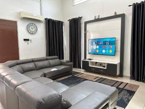 a living room with a couch and a flat screen tv at Bandar Melaka Family Bungalow Private Pool BBQ WiFi Netflix in Malacca