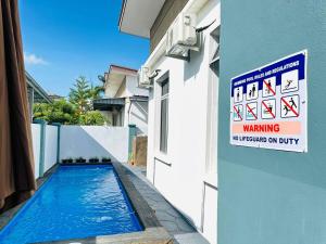 uma piscina com uma placa na lateral de um edifício em Bandar Melaka Family Bungalow Private Pool BBQ WiFi Netflix em Malaca