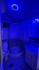 a bathroom with a toilet and a sink and a blue light at Greenside Apartment 3 in Pristina
