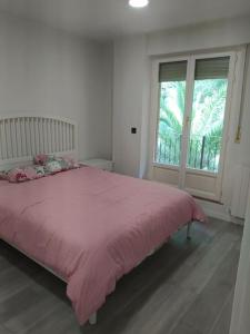 1 dormitorio con cama rosa y ventana en Precioso apartamento en Bilbao., en Galdakao