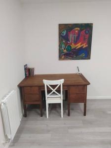 un escritorio de madera con una silla blanca y una pintura en Precioso apartamento en Bilbao., en Galdakao