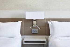 a bedroom with two beds and a lamp on the wall at AC Hotel by Marriott Los Angeles South Bay in Los Angeles