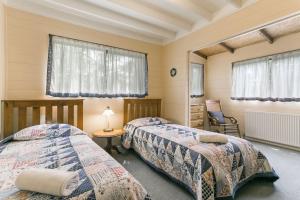 a bedroom with two beds and a chair and windows at Arcadia in Wentworth Falls