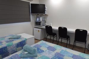 a room with a bed and chairs and a tv at Three Moon Motel in Monto