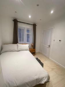 Un dormitorio con una gran cama blanca y una ventana en Dannifar Guest House, en Londres