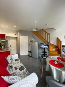 sala de estar con sofá rojo y cocina en La Citadine, en Bayeux