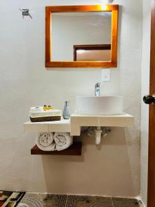 La salle de bains est pourvue d'un lavabo, d'un miroir et de serviettes. dans l'établissement CASA VICTORIA, à Chichén Itzá