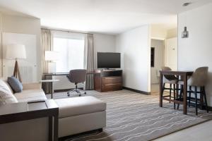 ein Wohnzimmer mit einem Sofa, einem Schreibtisch und einem TV in der Unterkunft Residence Inn by Marriott Anaheim Brea in Brea