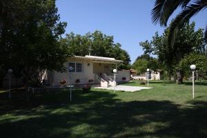 a house in a yard with trees and a grass field at Villa Vivere in Corfu Town