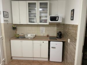 - une petite cuisine avec des placards blancs et un four micro-ondes dans l'établissement Viktória Apartman, à Balatonalmádi