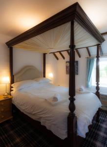 a bedroom with a canopy bed with white sheets at Riccal Dale Cottage in Helmsley