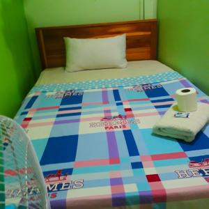 a bed with a colorful comforter and two towels at Archie's Budget Twin Room Rental in San Vicente