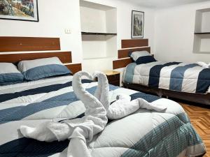 Dos toallas de cisne en camas en una habitación de hotel en Hospedaje Rumiñahui, en Ollantaytambo