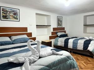 due cigni fatti con asciugamani sui letti in una stanza di Hospedaje Rumiñahui a Ollantaytambo