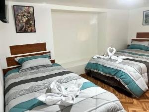1 dormitorio con 2 camas con flores blancas en Hospedaje Rumiñahui, en Ollantaytambo