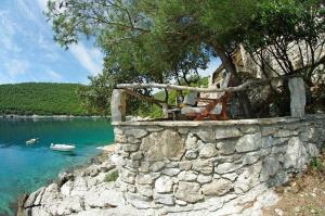 a stone wall next to a body of water at Secluded fisherman's cottage Cove Vela Studena, Brac - 20904 in Selca