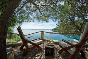 a table and two chairs under a tree near the water at Secluded fisherman's cottage Cove Vela Studena, Brac - 20904 in Selca