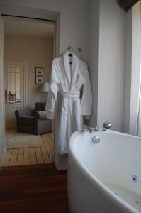 a white robe hanging on a wall next to a bath tub at Grand Hotel Belle Vue in De Haan
