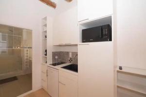 a white kitchen with a microwave and a sink at Design Suites Vieux Port in Marseille