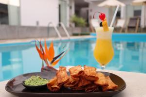 un plato de comida y una bebida junto a una piscina en La Estancia Hotel Ica en Ica