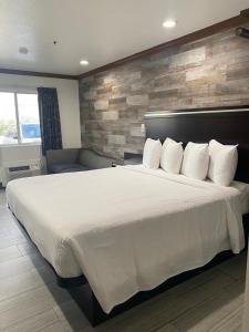 um quarto com uma cama grande com lençóis brancos e almofadas em Starlight Inn Huntington Beach em Huntington Beach