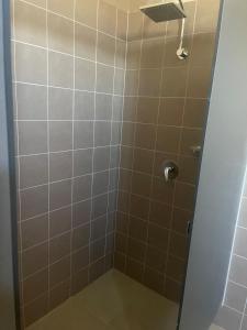 a shower with brown tile and a shower head at Bellbird Hotel in Cessnock