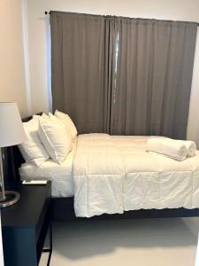 a bed with white sheets and pillows next to a window at Breathtaking 2-Bedroom Beachside Apartment in San Juan