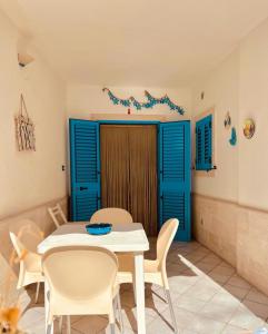 a dining room with blue shutters and a table and chairs at Baia camerini in Villanova di Ostuni