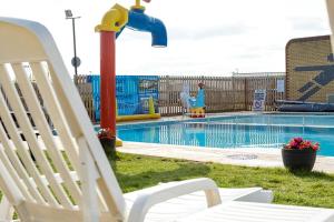 a white chair sitting next to a swimming pool at Luxury Whitstable Caravan in Seasalter
