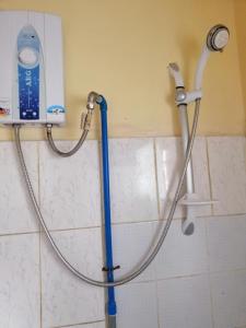 een douche in een badkamer met een blauwe slang bij Inn Maugay Bed and Bath in Sagada