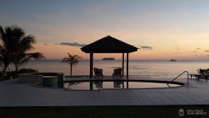 a swimming pool with a gazebo next to the ocean at Seacada- Beachfront - Pool - Panoramic Sunsets in George Town