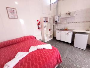 una pequeña cocina con una cama roja en una habitación en Zafiro Departamentos en Capilla del Monte