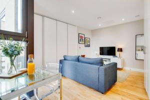 een woonkamer met een blauwe bank en een glazen tafel bij BR5 - Charming Studio Flat in heart of Borough in Londen