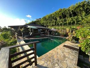 a house with a swimming pool in front of a house at Tehuarupe Surf Studio 2 in Haapiti