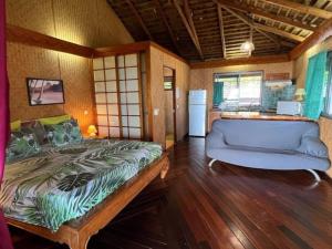 um quarto com uma cama e um sofá num quarto em Tehuarupe Surf Studio 2 em Haapiti