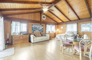 a living room with wooden ceilings and a table and chairs at Serenity Hale in Papa Bay Estates