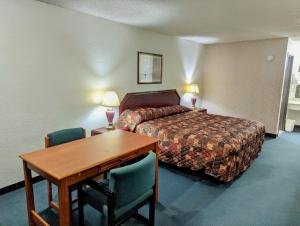 una camera d'albergo con letto, scrivania e tavolo di Luxury inn a Mustang