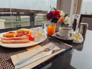a table with a plate of food and a cup of orange juice at Hotel De Khuvieng in Chiang Mai +291 photos