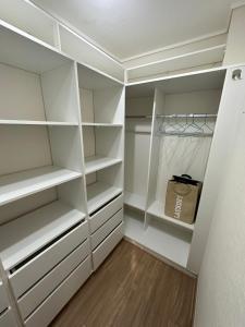 vestidor con armarios blancos y suelo de madera en Confortable Departamento VLC, en Santiago