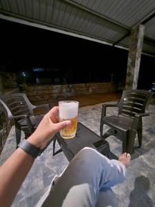 a person holding a glass of beer on a table at Tranquil Ridge Hilltop Bungalow in Hatton