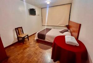 1 dormitorio con 1 cama con manta roja y silla en Hotel Bacastell, en Quito