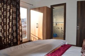a bedroom with a bed and a window at HIMALAYA INN in Pālampur