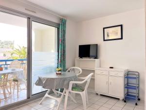 salon ze stołem i telewizorem w obiekcie Appartement familial avec piscine, terrasse et parking au Lavandou - 5 couchages - FR-1-251-487 w mieście Le Lavandou