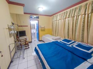 a bedroom with a blue bed and a tv at Hotel Fuente de Paz Managua in Managua