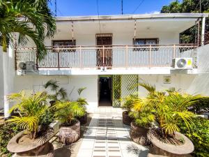 une maison blanche avec un balcon et des plantes dans l'établissement Hotel Fuente de Paz Managua, à Managua