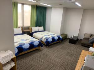 a hotel room with two beds and a couch at 4人で一緒に熊本の中心地の最も広く安価な部屋 KDY stay in Kumamoto