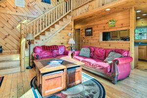 a living room with two pink couches and a staircase at Bryson City Cabin Rental with Mountain View, Hot Tub in Bryson City